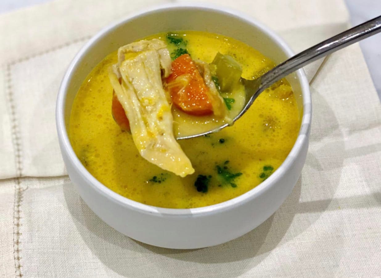 A bowl of Greek chicken soup with inflammation reducing turmeric, which has given it a wonderful golden colour. A healing soup.