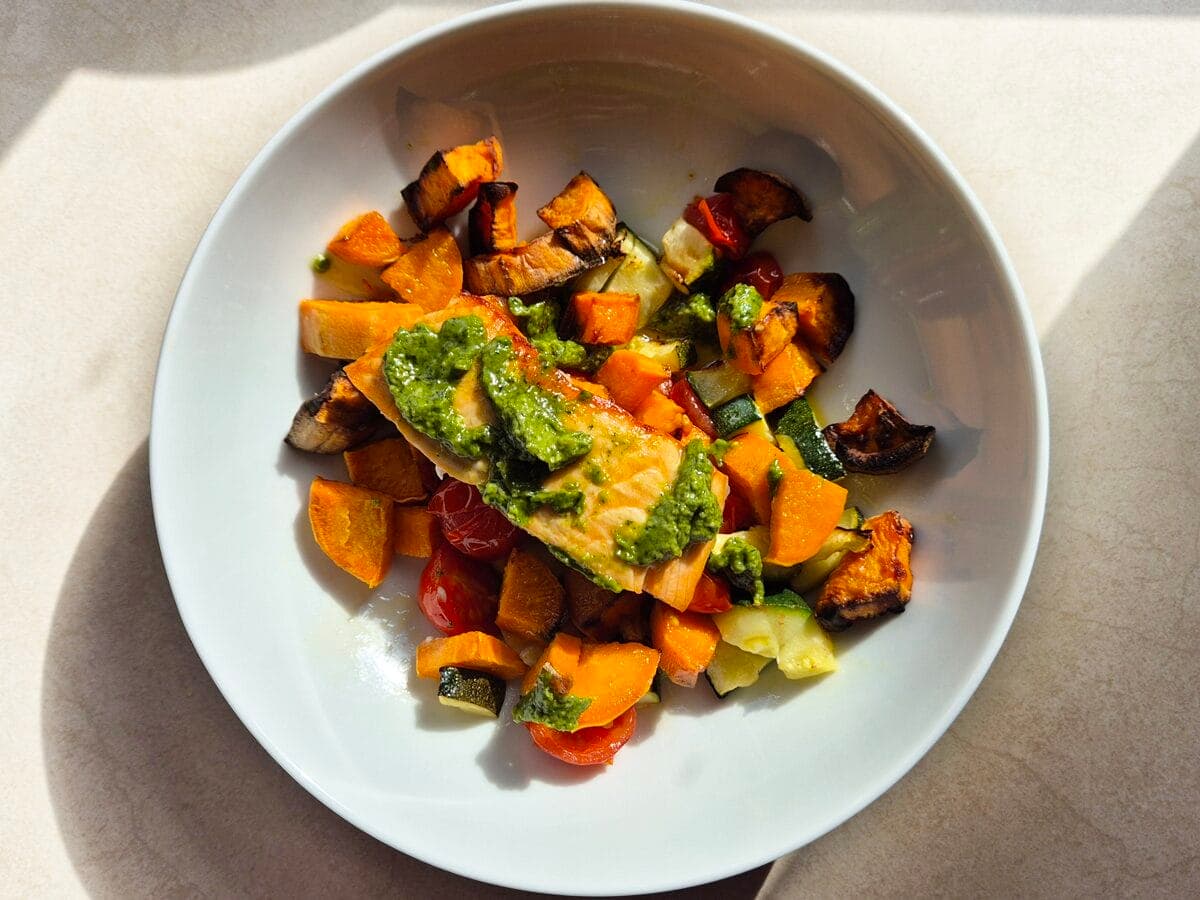 bowl of pesto salmon and roasted vegetables from a pesto salmon traybake recipe