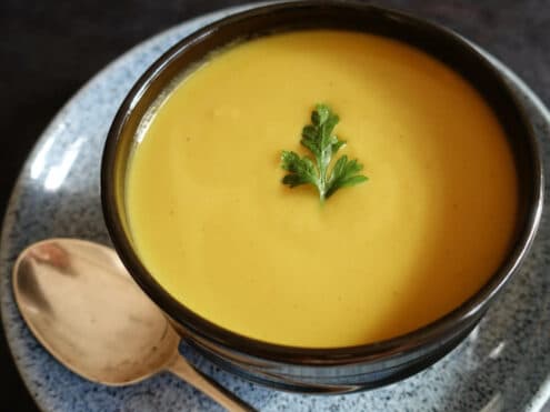 A bowl of creamy good carbs soup with a spoon by the side